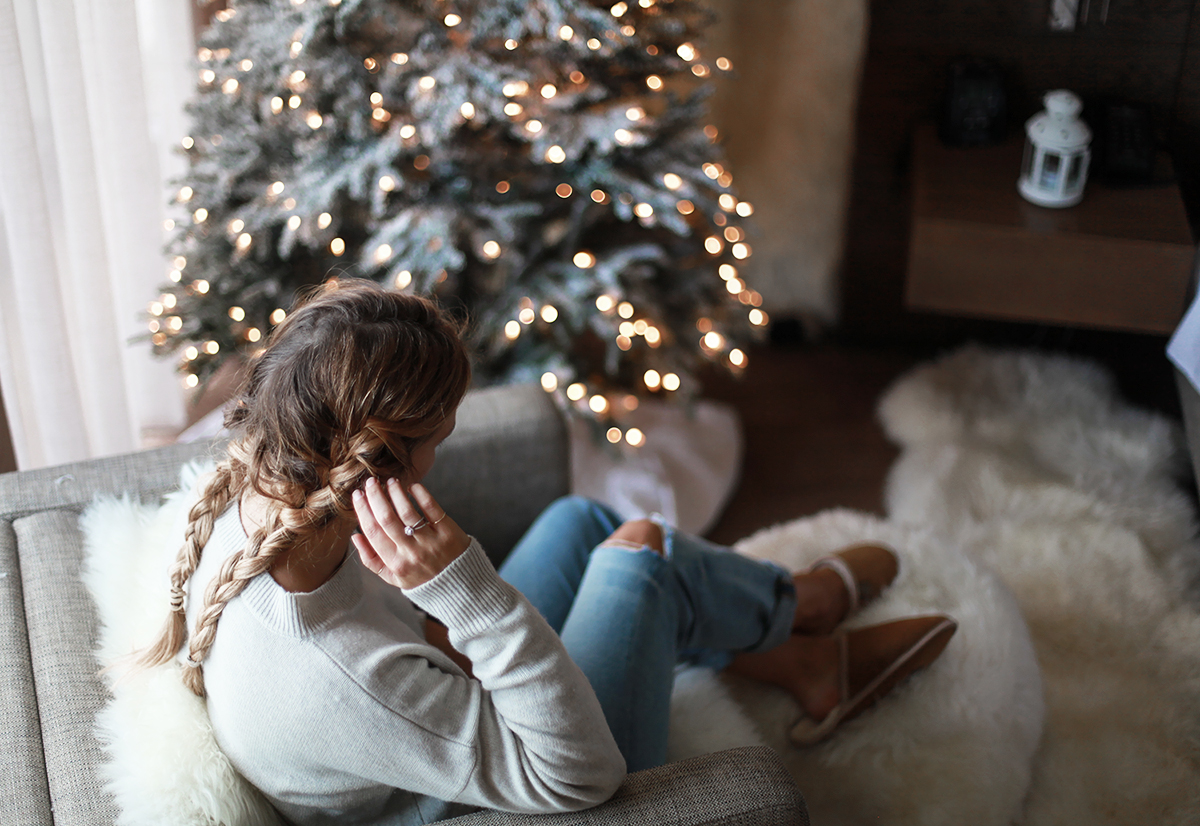 Lifestyle blogger Lisa Hamilton from See Want Shop with her Christmas tree wearing denim jeans, braided hair & knit sweater
