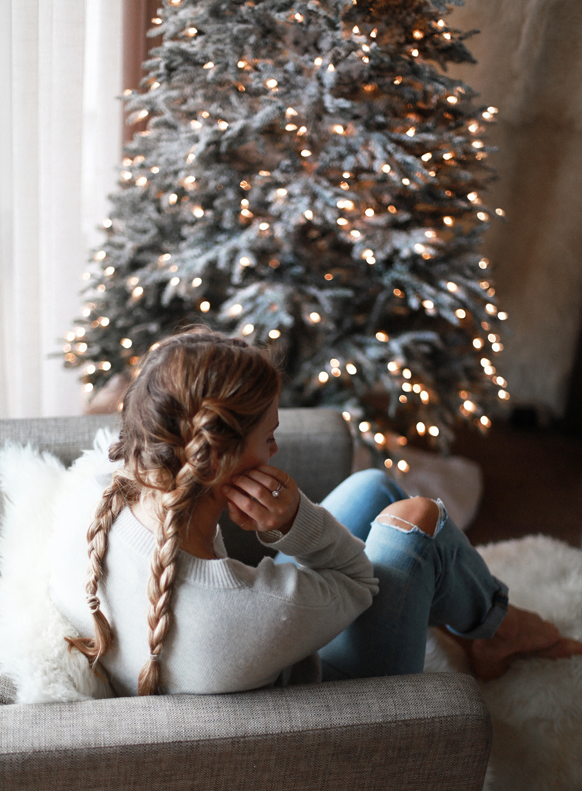 Lifestyle blogger Lisa Hamilton from See Want Shop with her Christmas tree wearing denim jeans, braided hair & knit sweater