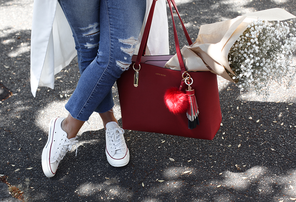 See Want Shop blogger Lisa Hamilton styling a red tote bag with pom-pom bag accessories, converse all stars & ripped jeans