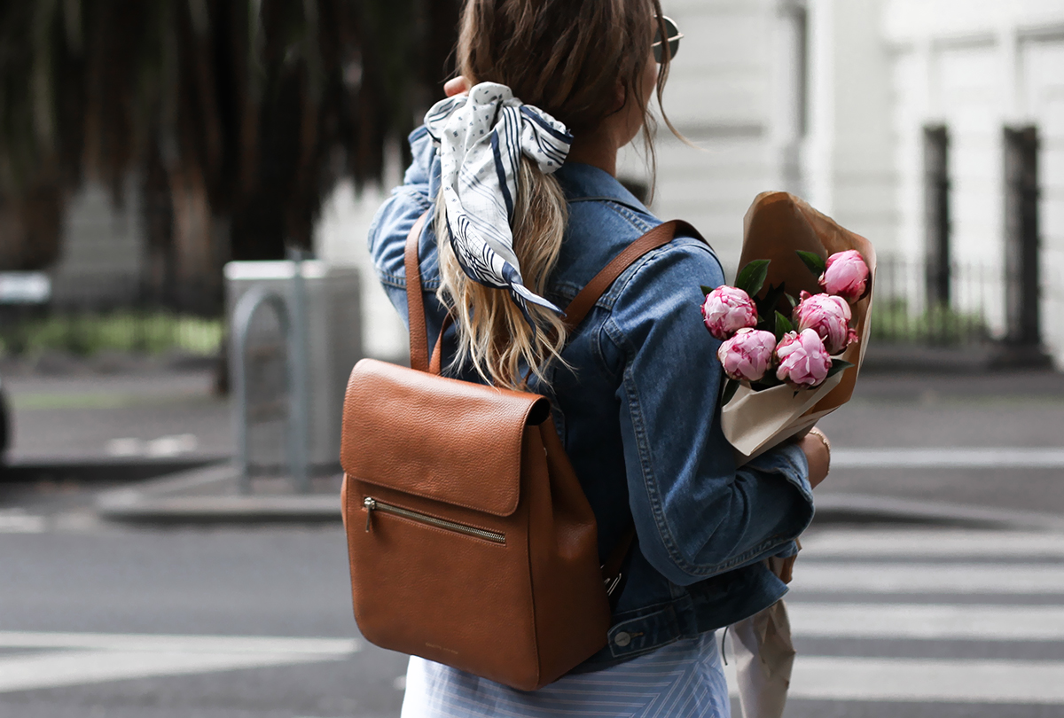 tan leather backpack and denim jacket